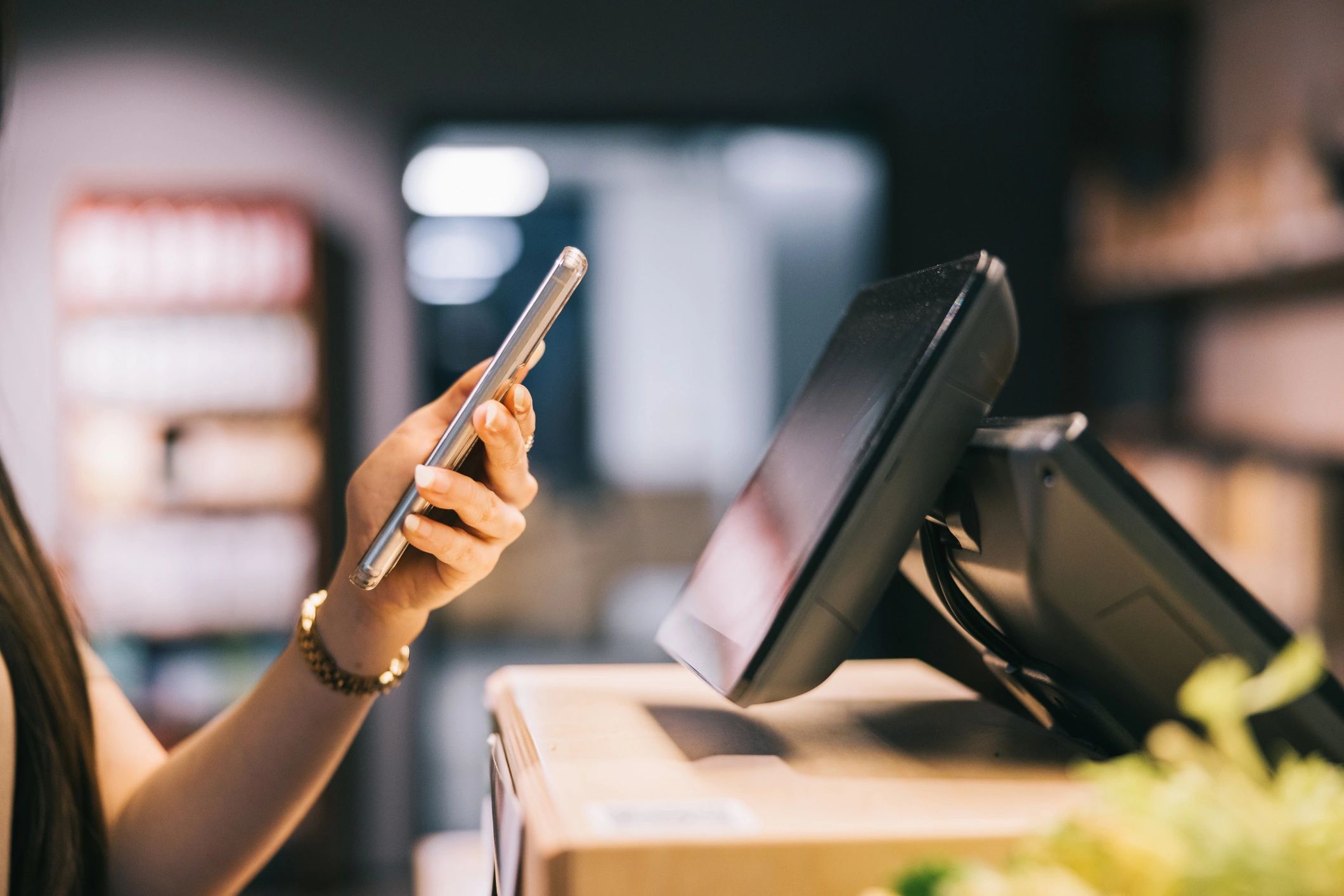 Woman holding smartphone and completing a payment at a self-service terminal